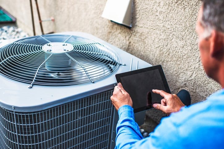 HVAC-contrator-diagnosing-air-conditioning-unit